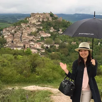 Accueil client avec parapluie devant un village, service VIP et transport privé personnalisé