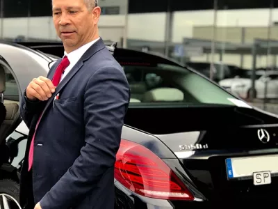 Chauffeur en costume près d’une berline Mercedes noire pour service VTC haut de gamme